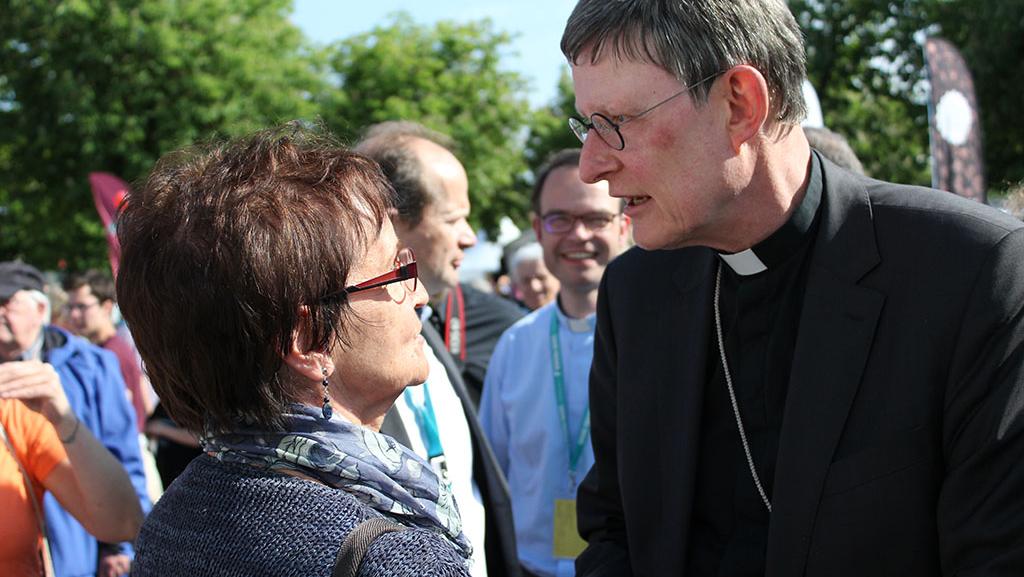 Kardinal Woelkispricht mit einer Besucherin am Stand des Erzbistums Köln