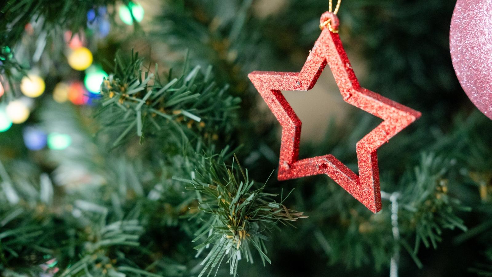 wooden Christmas tree toy in the shape of a star hanging on a branch, close-up