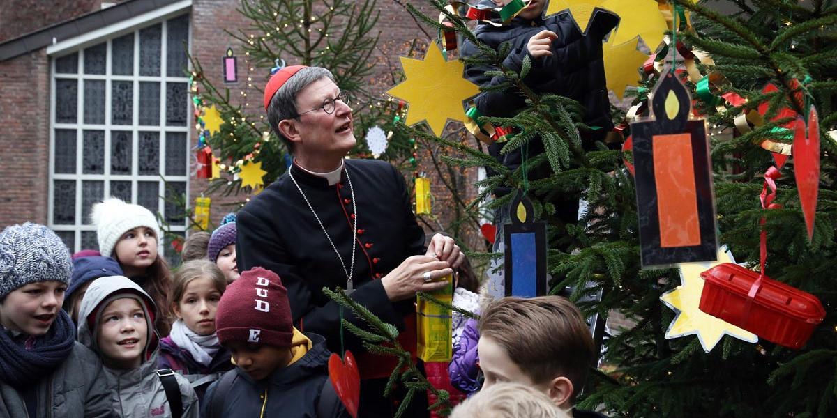 Der Kölner Erzbischof Rainer Maria Kardinal Woelki hängt den selbstgebastelten Weihnachtsschmuck auf, den die Kinder der Katholischen Grundschule Remigius in Leverkusen mitgebracht haben.