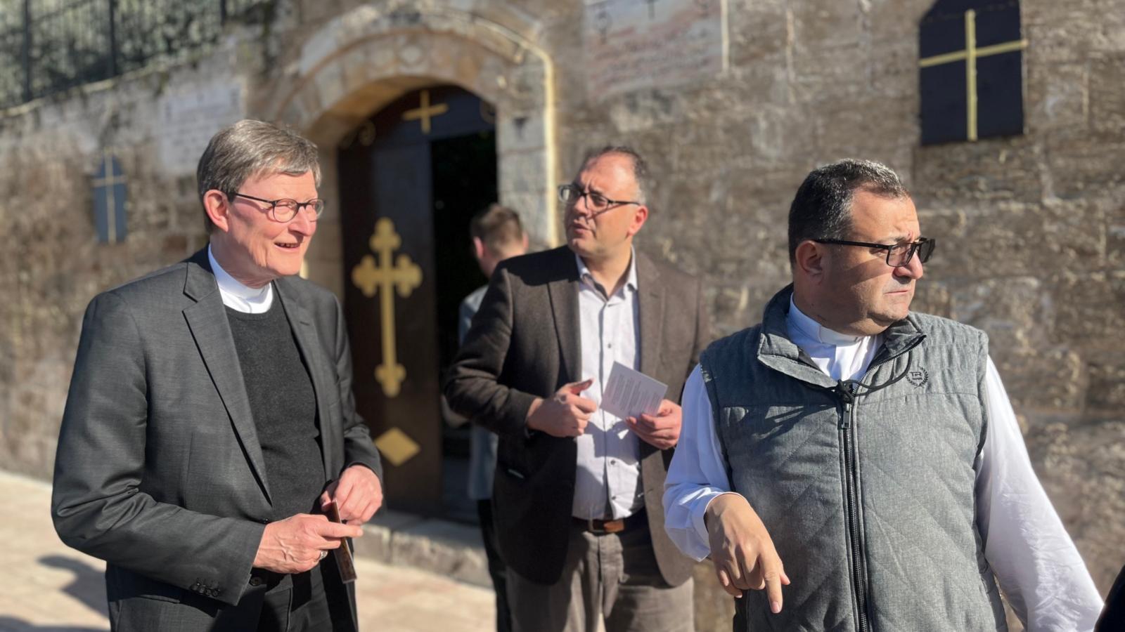 Ein Foto zeigt Kardinal Woelki vor der Kirche einer Gemeinde in Burqin.