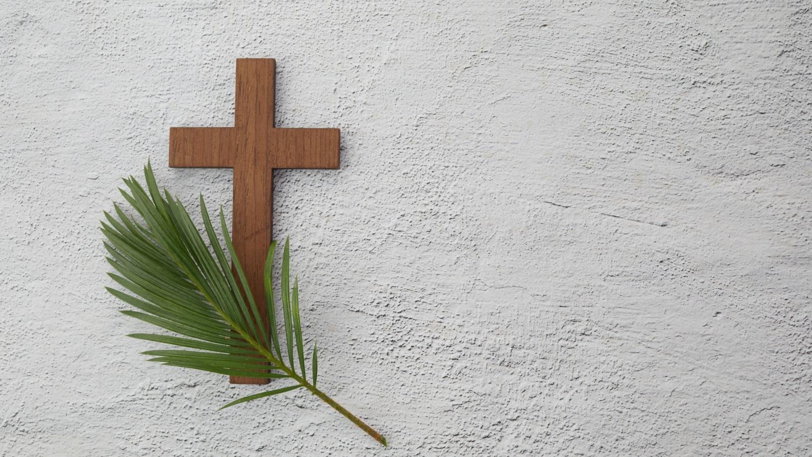 Palm sunday background. Cross and palm on grey background.