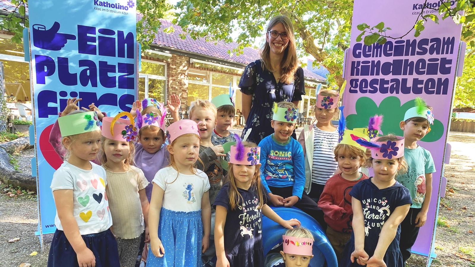 Ein Foto zeigt eine Gruppe Kindergartenkinder mit einer Erzieherin im Garten des Kindergartens.