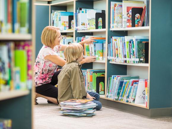 Frau mit Kind am Bücherregal