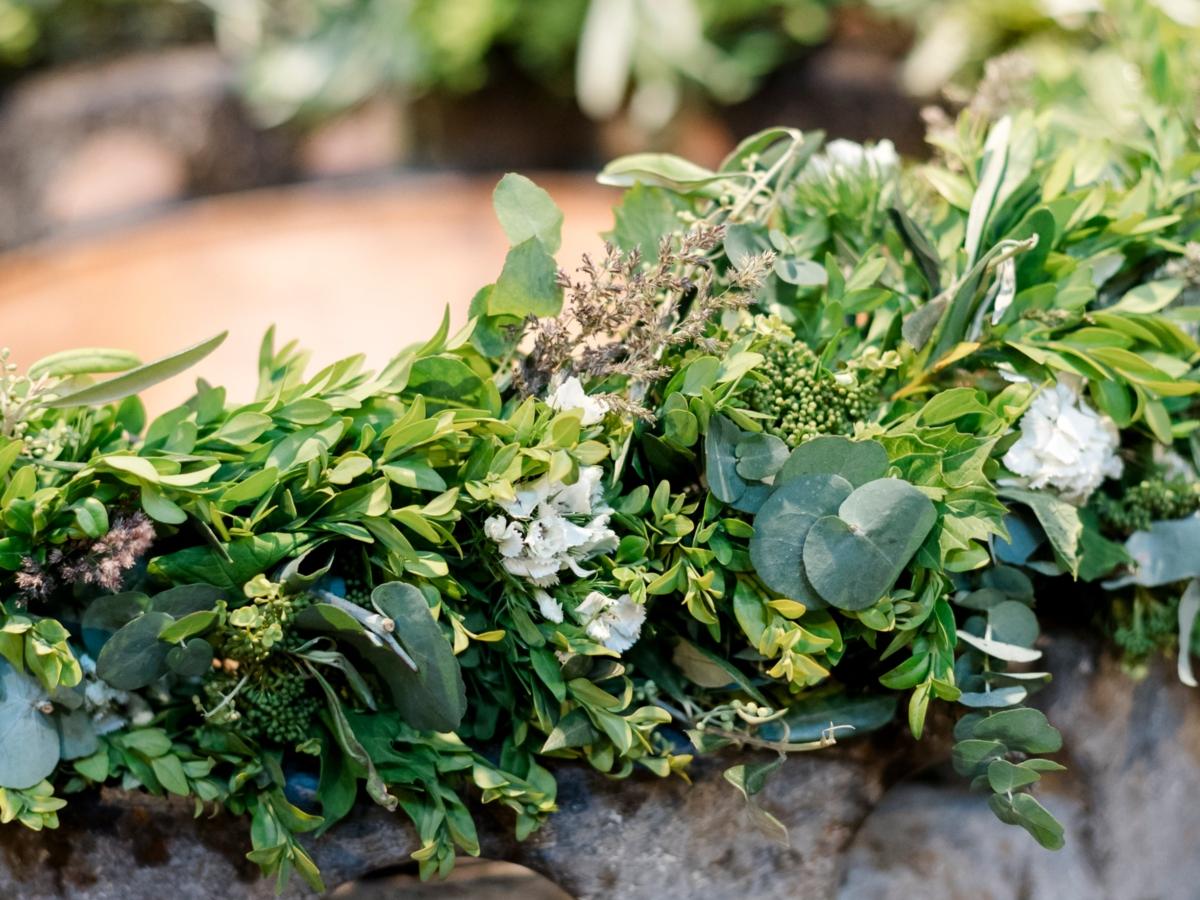 Steinernes Taufbecken mit Blumenkranz.