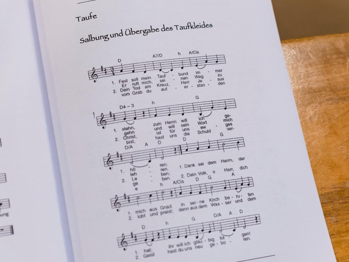 Aufgeschlagenes Liedheft auf Kirchenbank.