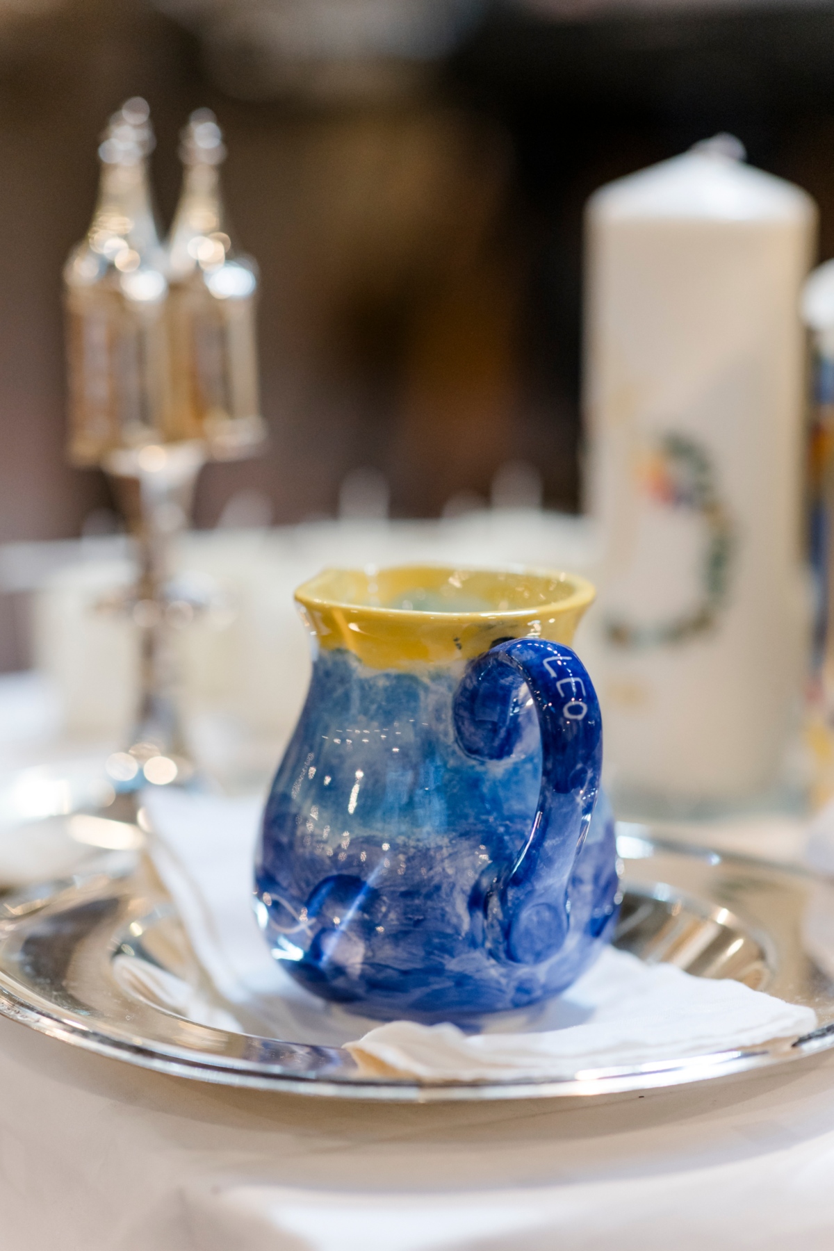 Taufwasser, Ölgefäß und Kerze auf Tablett.