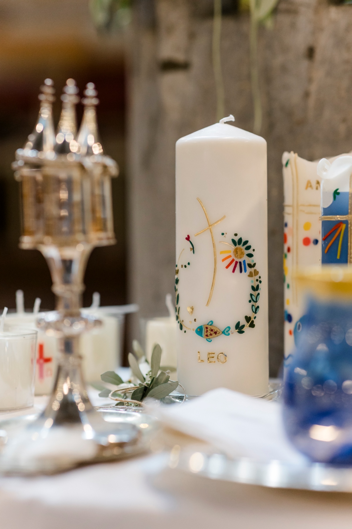 Taufkerze, Ölgefäß und Wasserkrug auf Tisch.