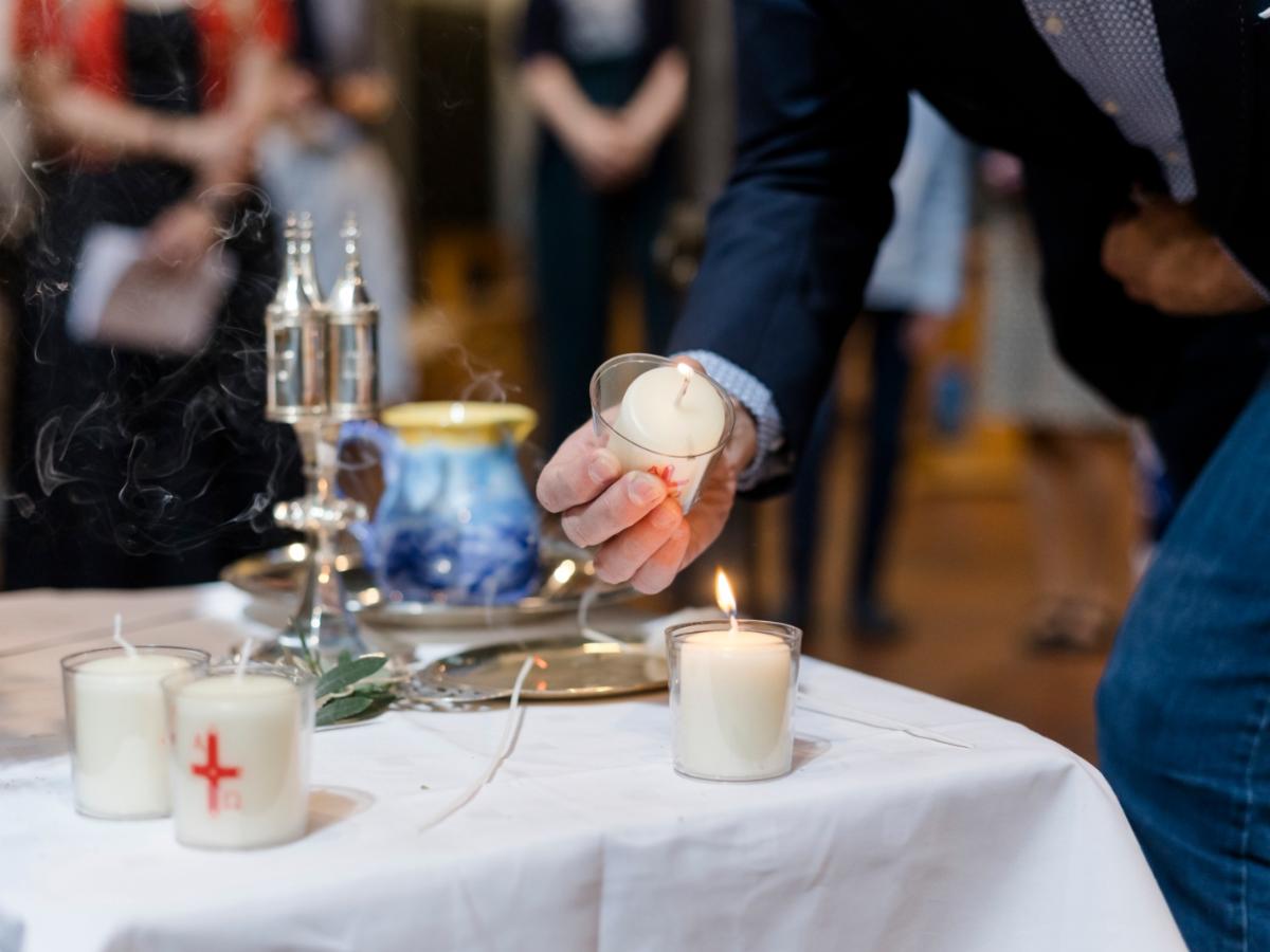 Taufkerze wird an brennender Osterkerze entzündet.